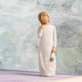 Willow Tree Remember, 5.5”h hand-painted standing resin figure in cream dress holding drooping wire flower in hand, in front of grey painting