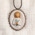 Oval bas-relief carving of figure holding sprig of rosemary, edged in pierced-metal filigree with brown elastic ornament loop