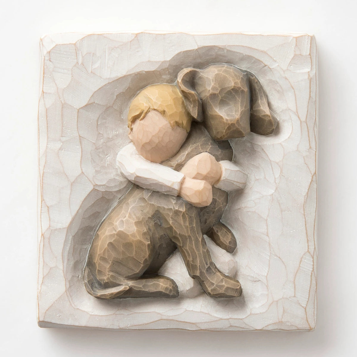 Close up of carved white square stone - in the middle is faceless young boy holding larger brown dog