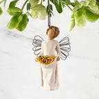 Figure with darker skin, in cream dress with wire wings and wavy brown hair, holding up skirt filled with yellow sunflowers. Hook and loop affixed to figure’s head