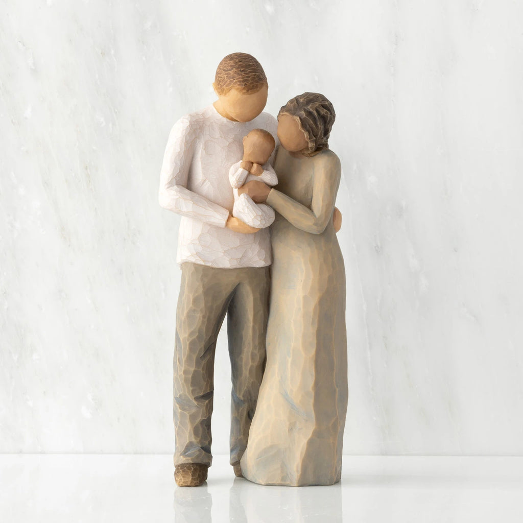 Front view of standing couple, woman has darker skin and hair; man has lighter skin and hair, holding a baby between them.