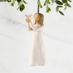 Figure in cream dress, holding white dove on extended arms. Hook and loop affixed to figure's head