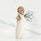 Small brunette angel figurine in white dress holding golden cat