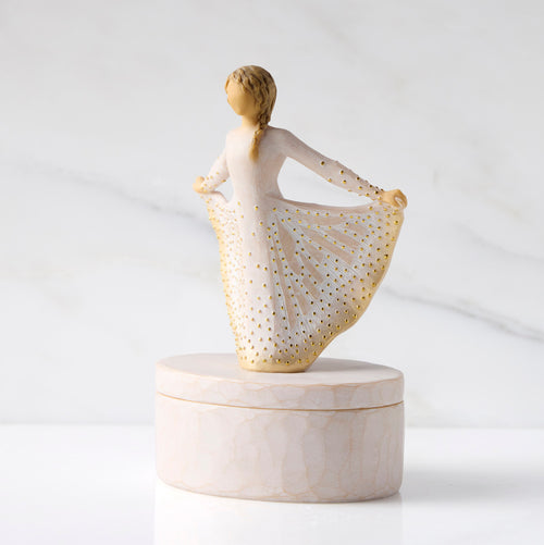 Left view: oval resin box, with 3-D figure atop lid, in cream and gold carved dress
