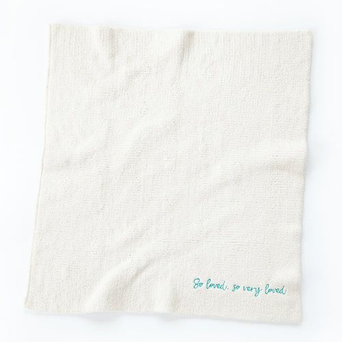 Overview of white towel with 'so loved, so very loved' in light blue in the right corner