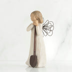 Young brunette girl figurine in white dress holding brown shovel