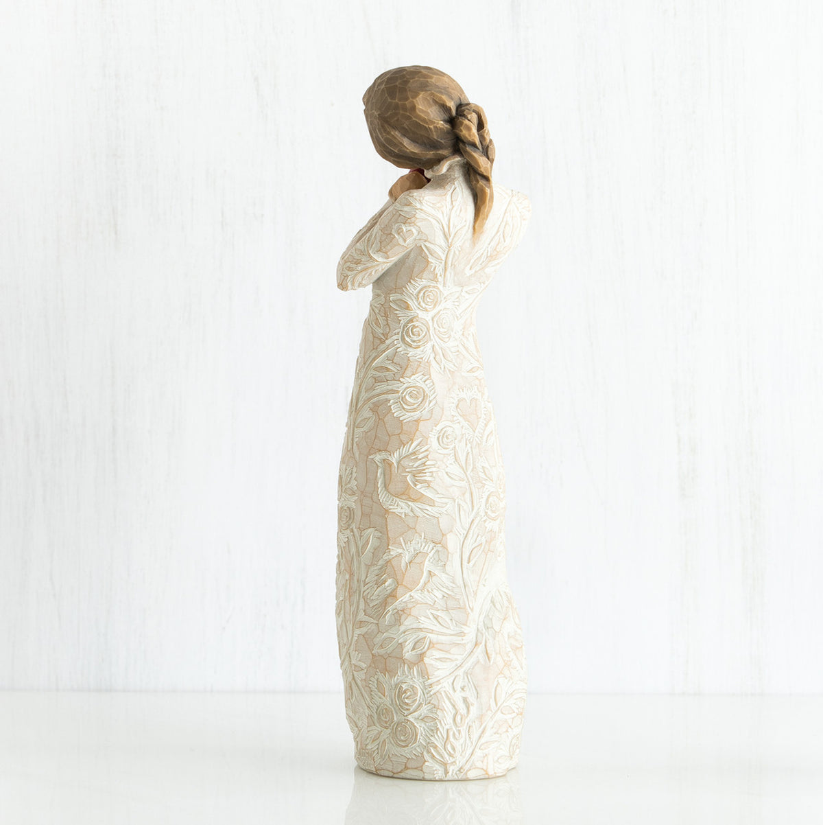 Side view of younger girl brunette figurine wearing white dress facing the other side