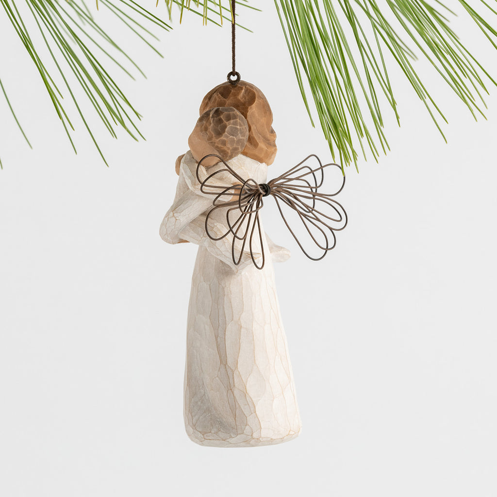 Side view figure of female in cream dress with wire wings, holding baby in cream onesie, with ornament loop on head
