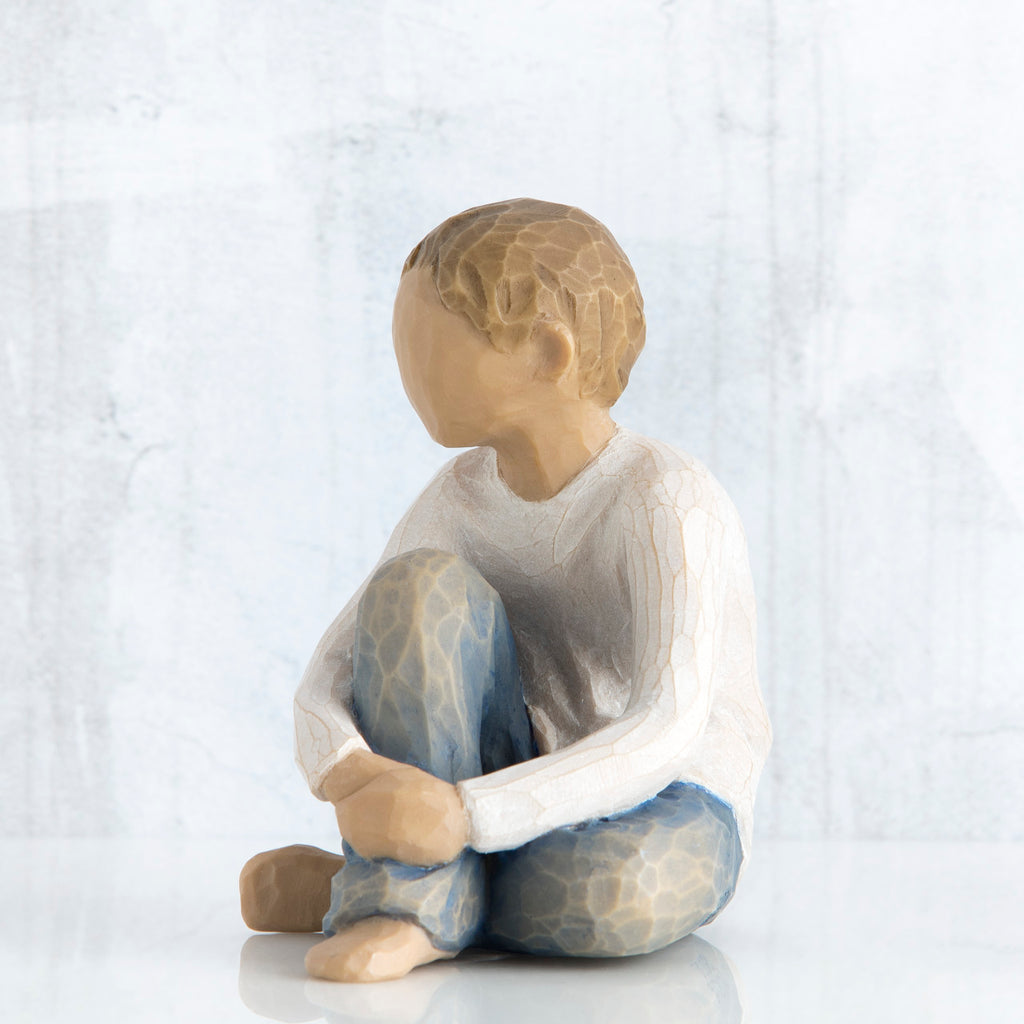 Young brunette boy sitting in white shirt and blue jeans facing close to the front - white background
