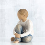 Young brunette boy sitting in white shirt and blue jeans facing close to the front - white background