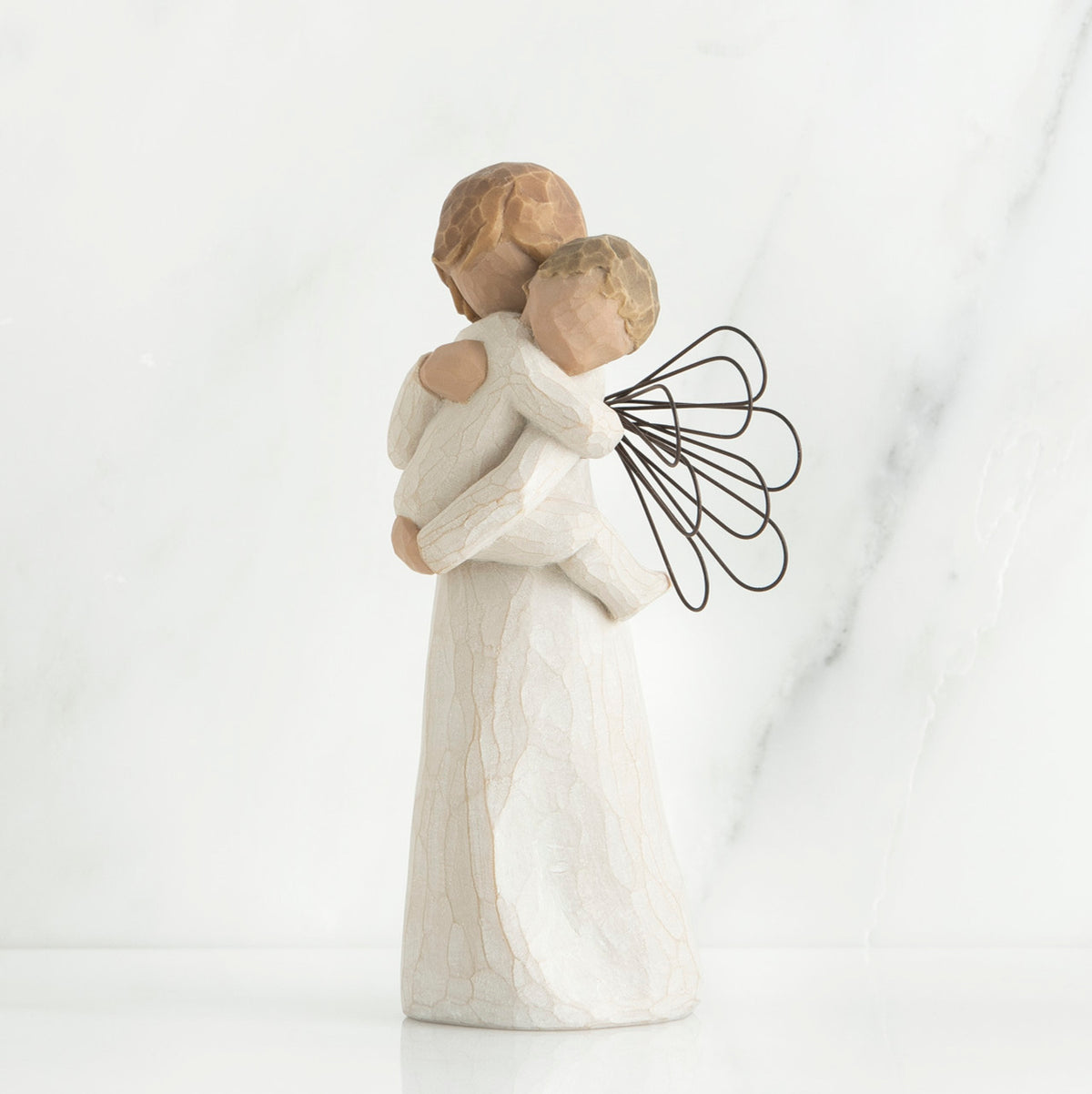 Angel figurine with black wire wings  in white holding baby in her arms
