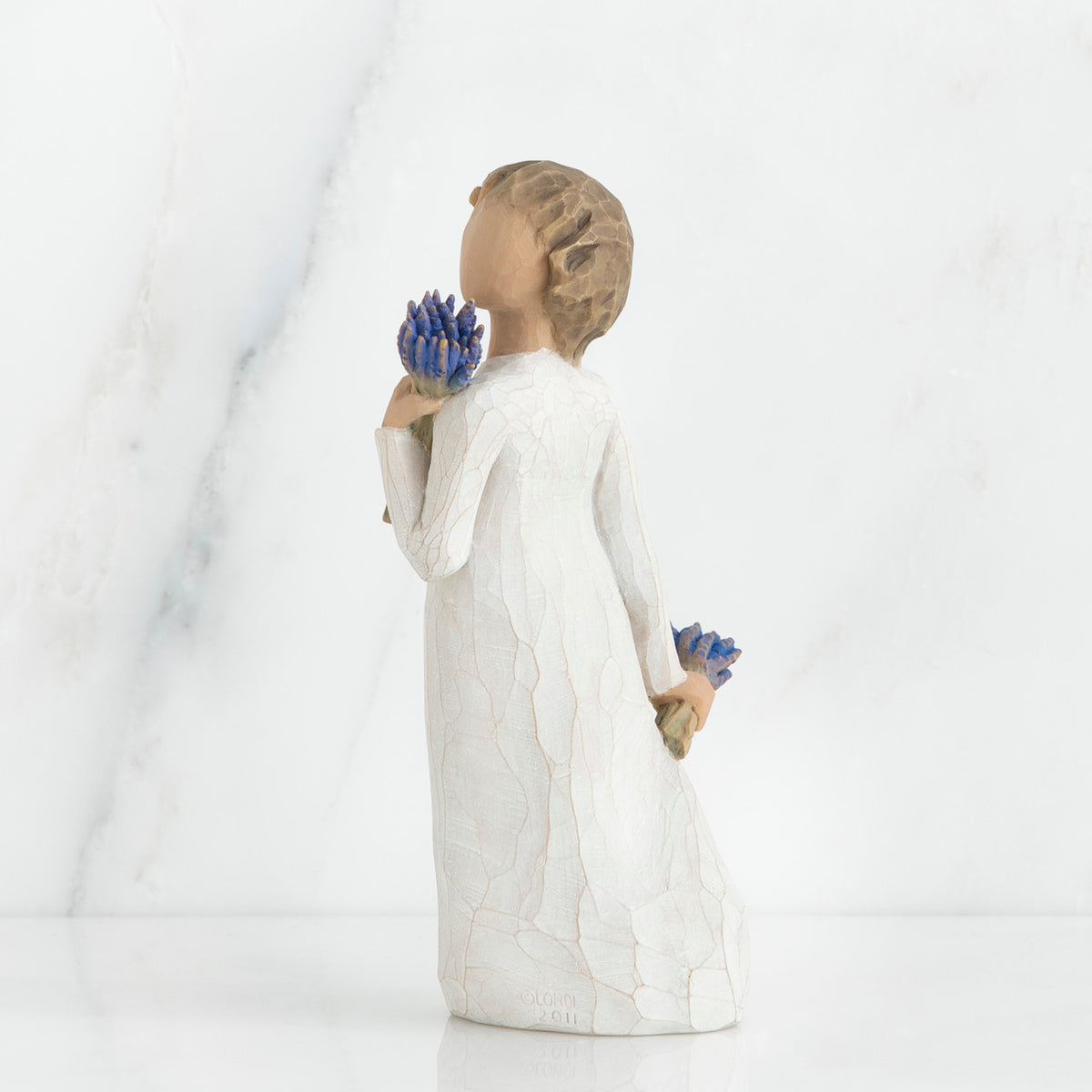 Brunette girl figurine in white dress holding blue flowers