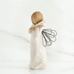 Side view of blonde angel figurine holding white seashell to her ear
