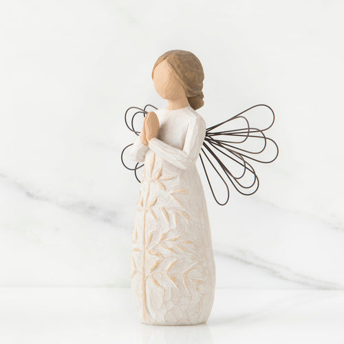 Side view of brunette angel figurine in white dress holding hands in prayer with black wire wings