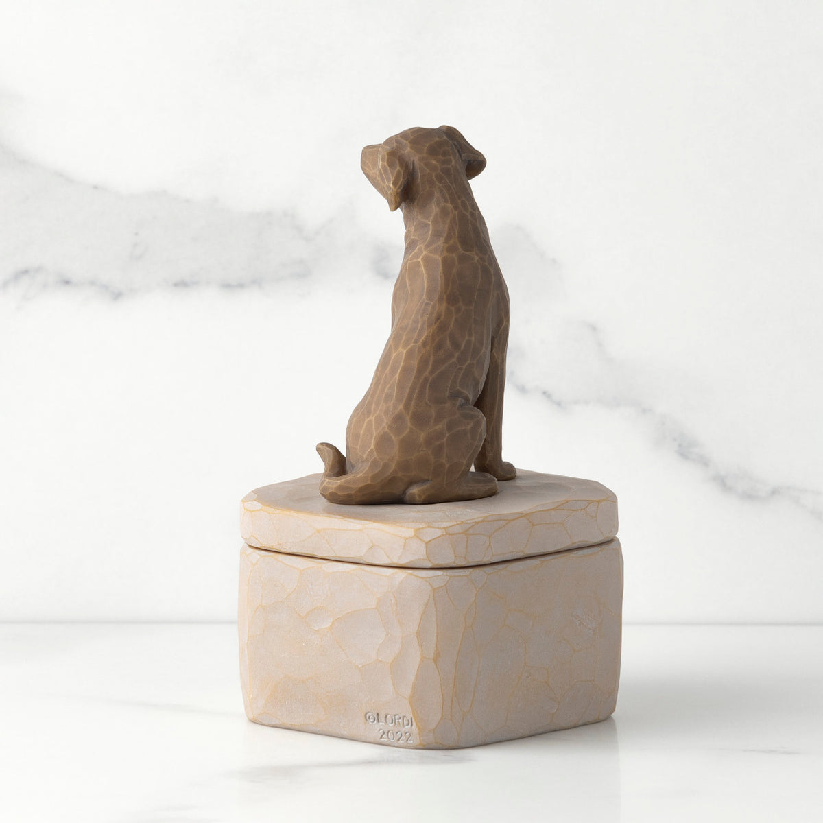 Back: gray square resin box with lid, 3-D figure of dark color dog atop lid