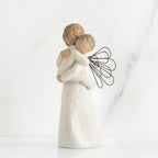 Angel figurine with black wire wings  in white holding baby in her arms