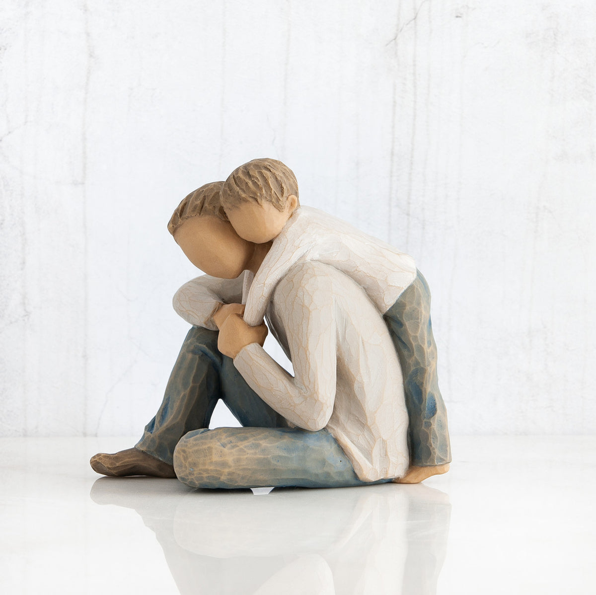 Faceless man figurine with little boy's arms around him - both weraing white shirts with blue jeans
