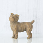 Figure of small brown dog standing on four legs, facing left