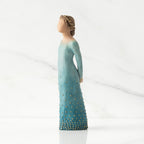 Facing left: Lighter-skin figure, arms clasped behind back, hair and deep blue ombré garment dotted with gold leaf