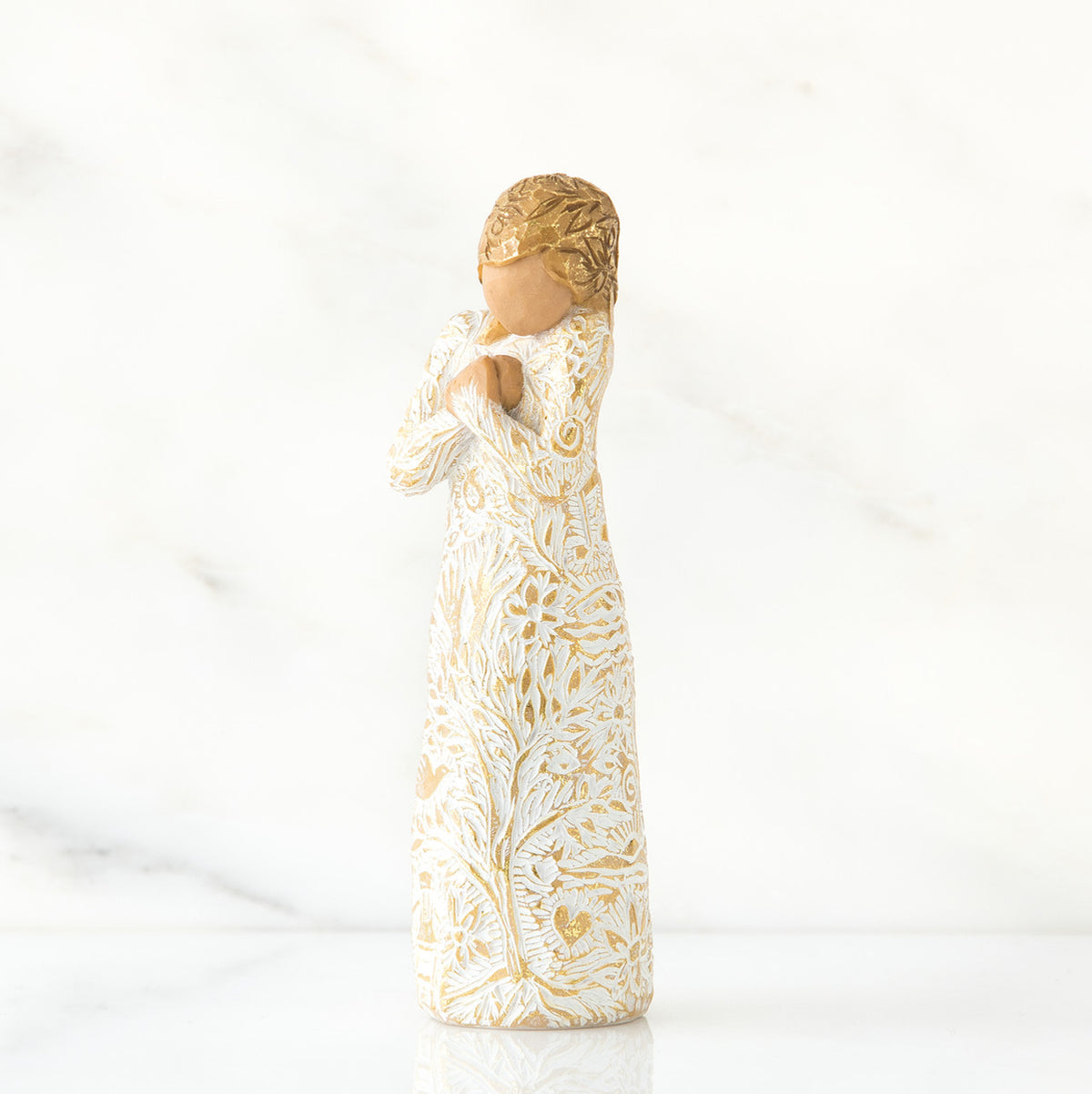 Gold haired woman in white/gold dress facing forward with arms to her chest