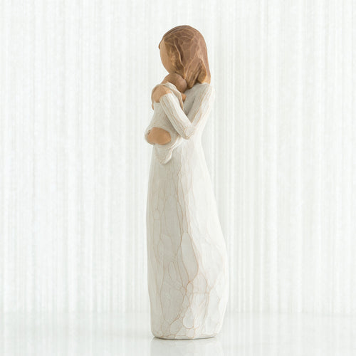 Side view of brunette girl figurine in white dress holding baby
