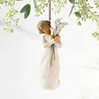 Front view of figure in cream dress with short hair holding tall bouquet of white calla lillies, ornament hook affixed to top of head