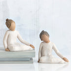 Two young girl figurines sitting in white dresses facing forward
