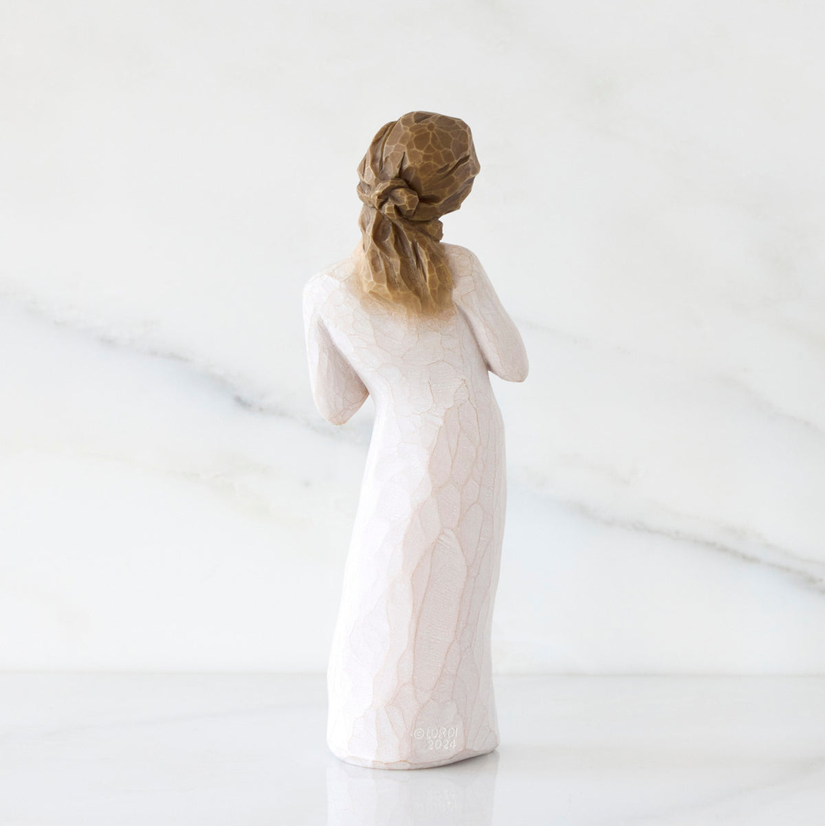 Back view: Standing figure in cream dress with hands to heart in empathetic gesture