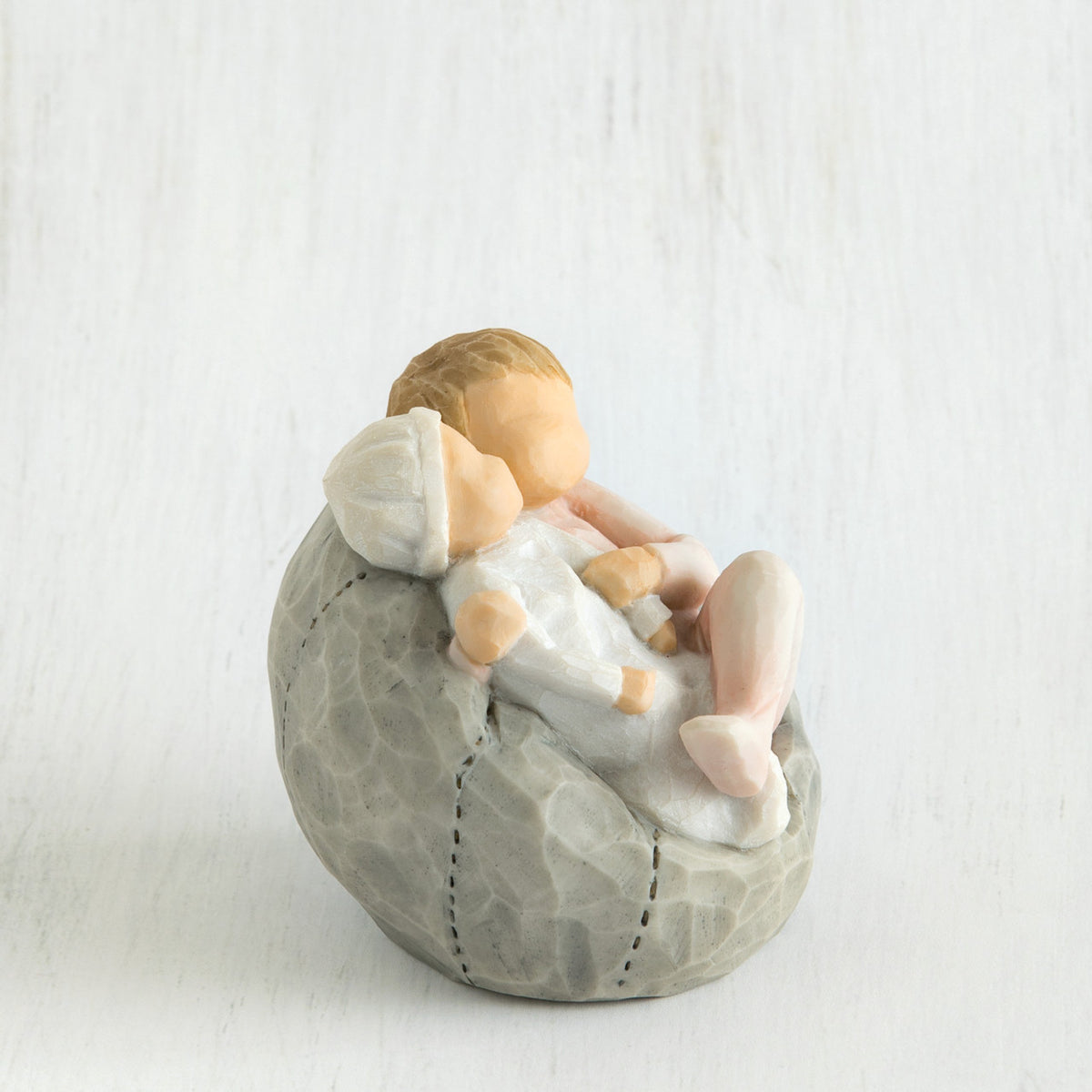 Small baby figurines laying on grey bean bag figurine