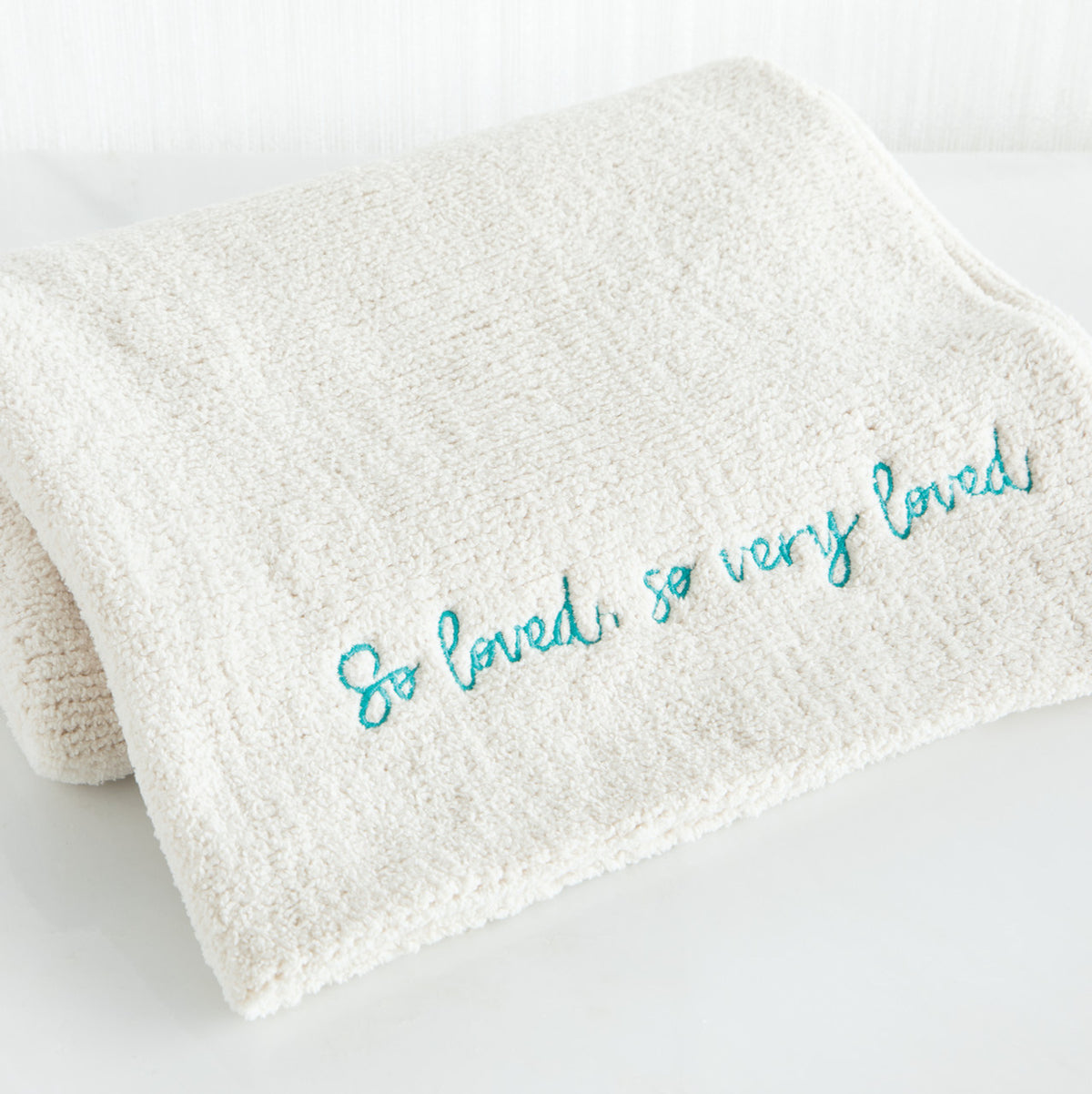 Close view of white towel with 'so loved, so very loved' in light blue
