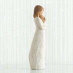 Side view of brunette woman figurine in white dress holding baby
