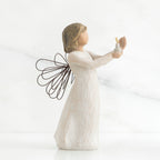 Side view of brunette girl figurine in white dress with brown wire wings holding up candle