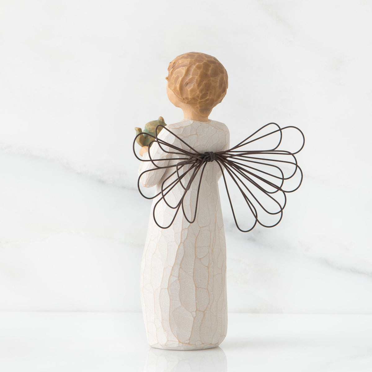 Back view of blonde girl figurine in white dress with black wire wings