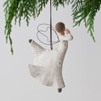 Side view of angel figurine ornament hanging from green christmas tree