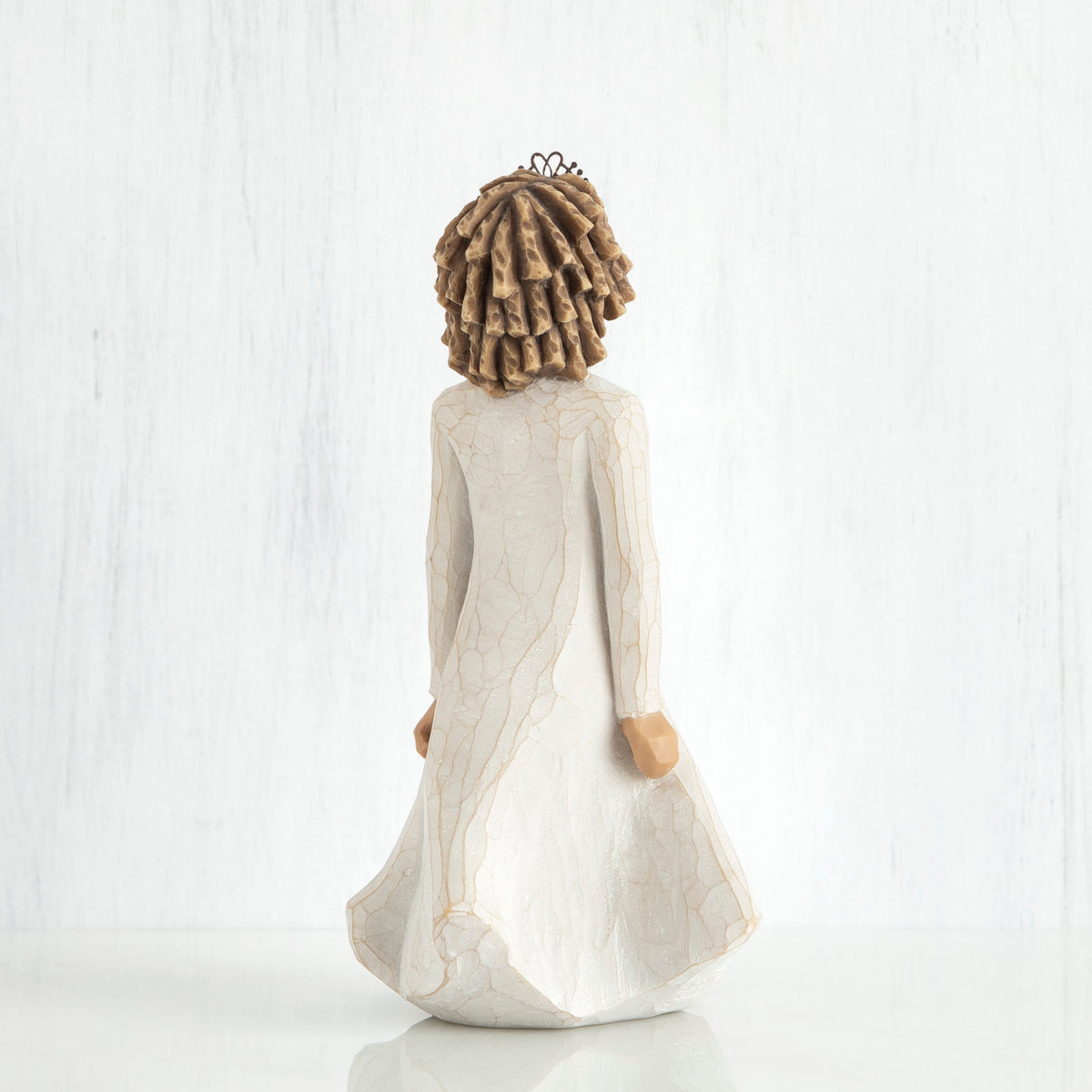 Back view of curly hair girl figurine in white dress standing up