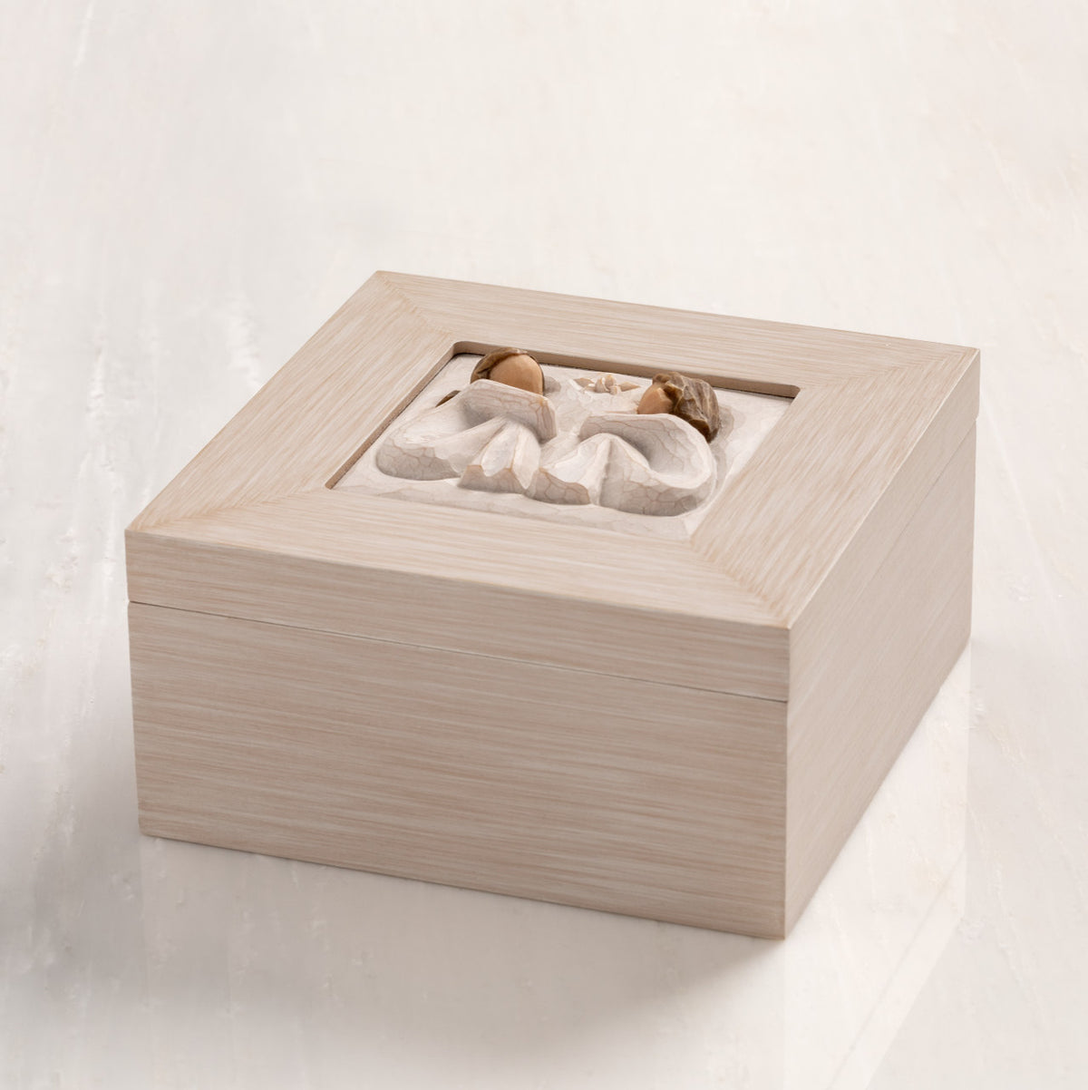 Side View: Cream wood box with hinged lid. Inset bas-relief plaque of two seated girls, facing each other.