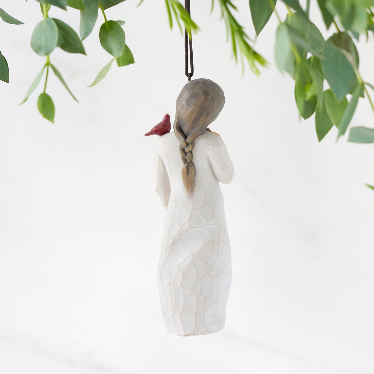 Back view of figure in cream dress with cardinal red bird perched on shoulder, hook & loop in head