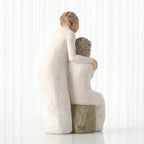 Back view, seated older female in cream dress, with younger female in cream dress, standing at her shoulder, hands embracing