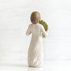 Back view of young girl with bangs and short brown hair holding up a green, leafy wreath