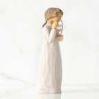Right-facing view, standing female figure in cream dress, holding gold wire circle in which is written 'love you'