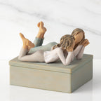 Right profile of closed rectangular blue-gray resin box, sculpture of two reclining girls on box lid