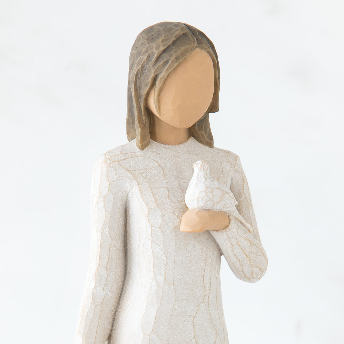 Close view of brunette girl figurine in white dress holding white dove