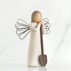 Young faceless girl figurine in white dress with black wire wings holding brown shovel