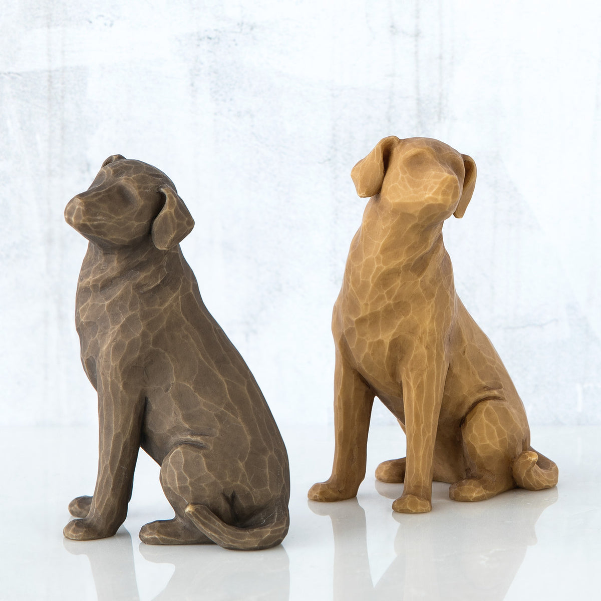 Set of two dog figurines sitting -one is brown and one is golden