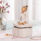 Willow Tree The Dancer Keepsake Box, 3.0"w x 3.25”d hand-painted resin box with 2.25”h figure of seated dancer in cream leotard affixed to lid, on table with jewelry inside