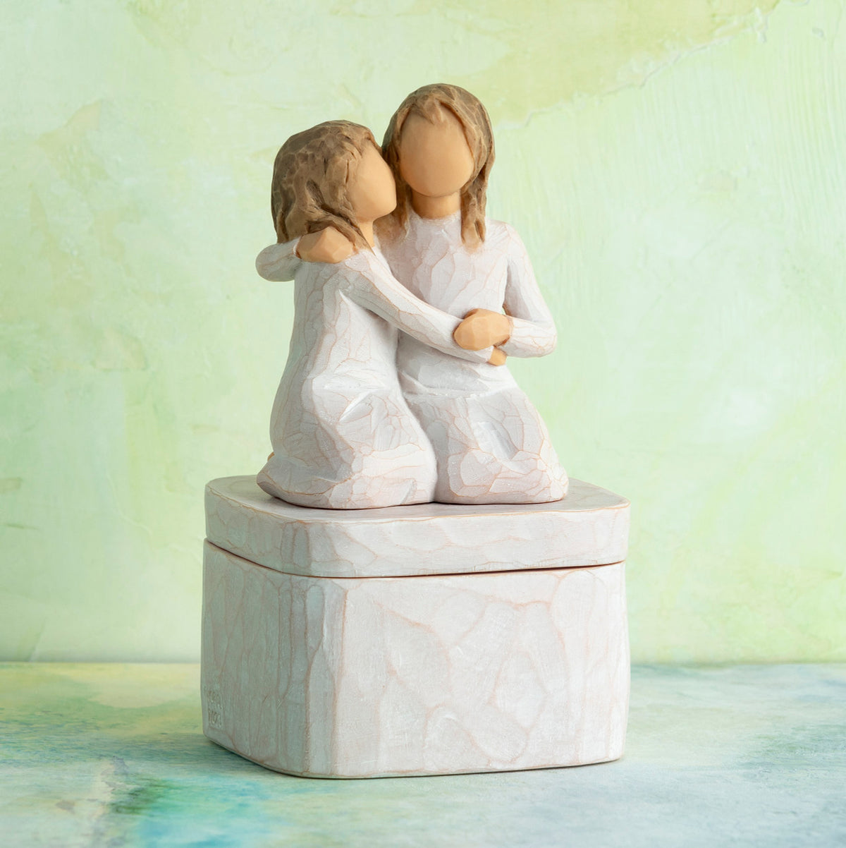 Willow Tree Sister mine Keepsake Box, 3"sq hand-painted resin box with 3.5”H figure of two kneeling girls in cream dresses, arms around each other, affixed to lid, in front of green painting