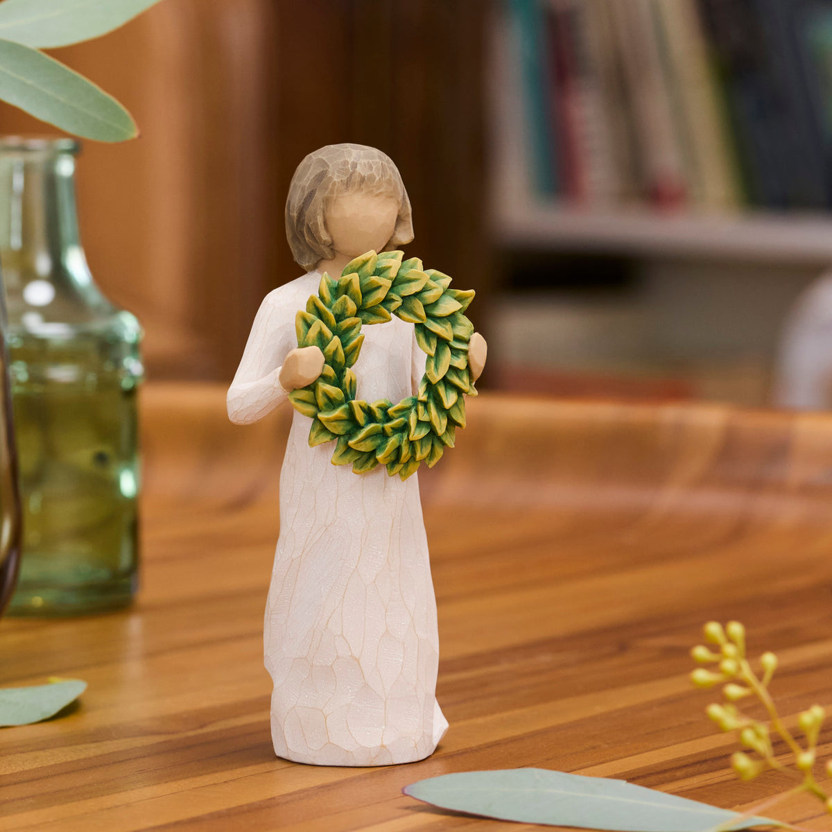 Willow Tree Magnolia, 5.5”h hand-painted standing resin figure in cream dress, holding green magnolia leaf wreath, on wooden desk