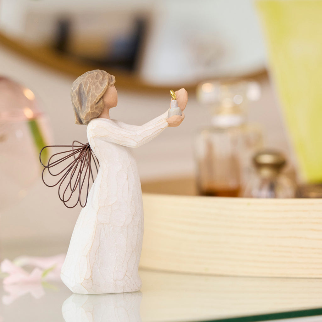 Willow Tree Angel of Hope, 5.5"h hand-painted standing resin figure in cream dress with wire wings, holding candle with gold-leaf flame in hands, on bedroom dresser