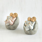 Set of two baby figurines being held by their siblings on grey beanbags