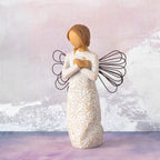 Willow Tree Remembrance, 5”h hand-painted standing resin angel figure in cream dress carved with symbols of nature, wire wings, crossed hands under small gold-leaf heart, in front of pale purple painting